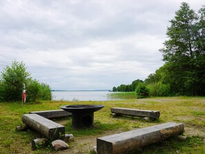 A lakeside campsite with a fire pit, benches, and a walking path. - 8 Person Holiday Home in Adelso (Adelso)