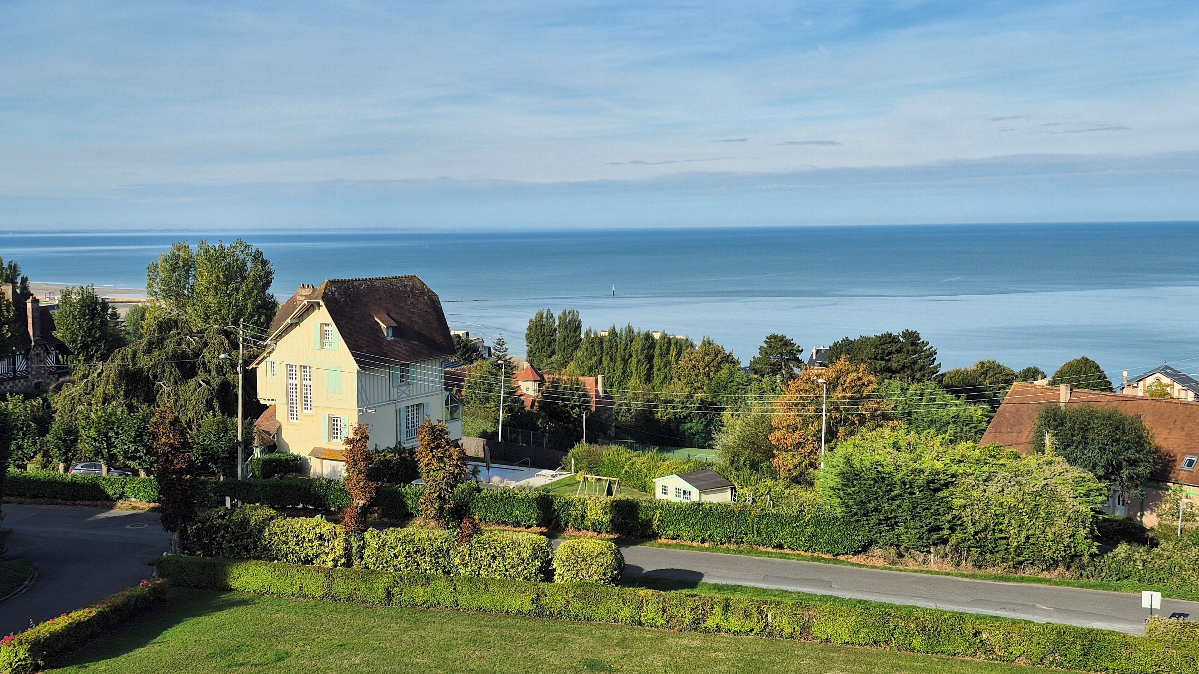 A coastal residential area with houses, a road, and a view of the sea.