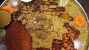 Un gran plato de biryani con diferentes carnes, verduras y guarniciones.