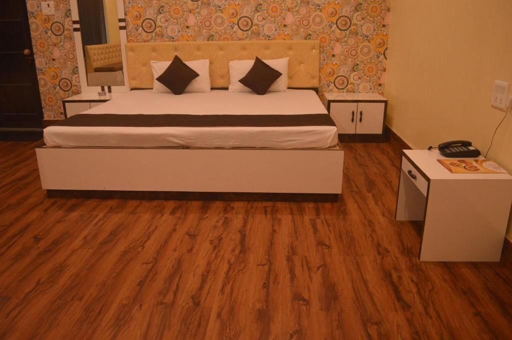 Un dormitorio con una cama grande, dos mesitas de noche, un armario y un papel tapiz estampado.