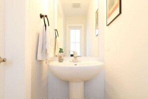 A bathroom with a white sink, a towel hanging on the wall, and a window in the background. - Spacious Binbrook Retreat | FREE Parking & Wi-Fi (Hamilton)