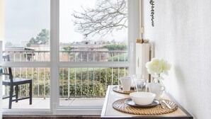 Un coin repas avec une table dressée pour deux personnes, une vue sur l’extérieur et une chaise.