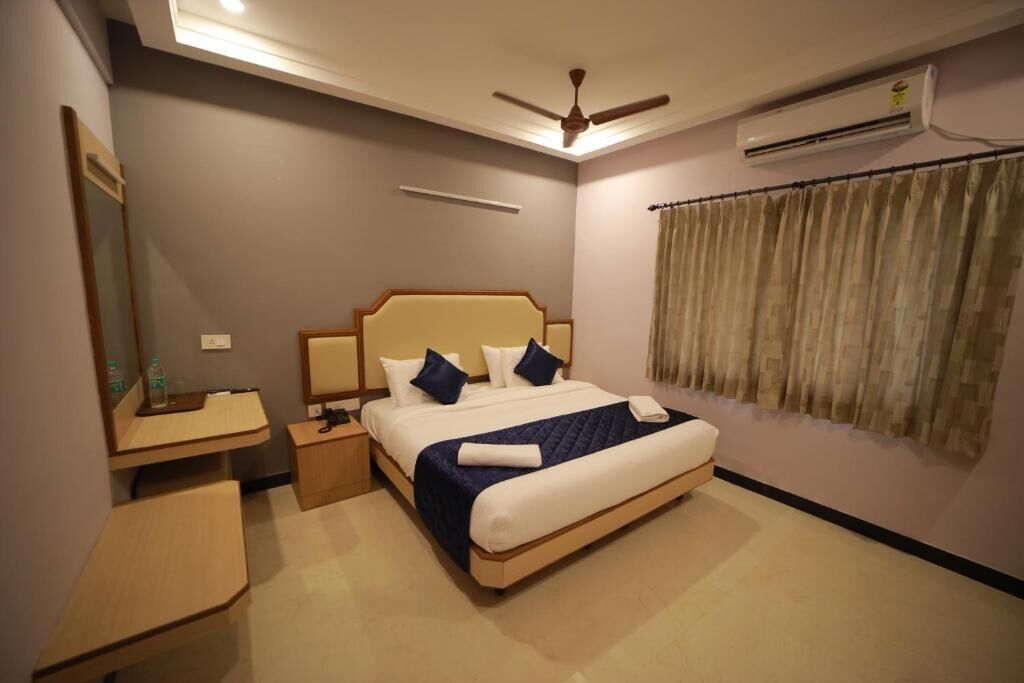 A hotel room with a bed, bedside table, and a desk.