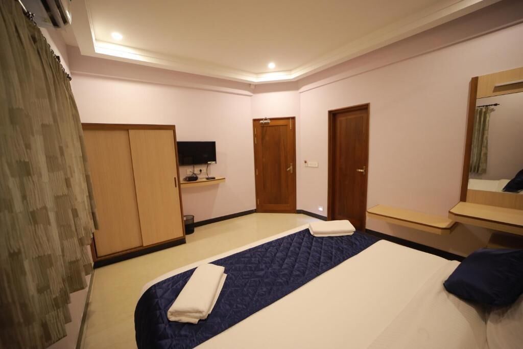Habitación de hotel con cama, televisor, armario y espejo.