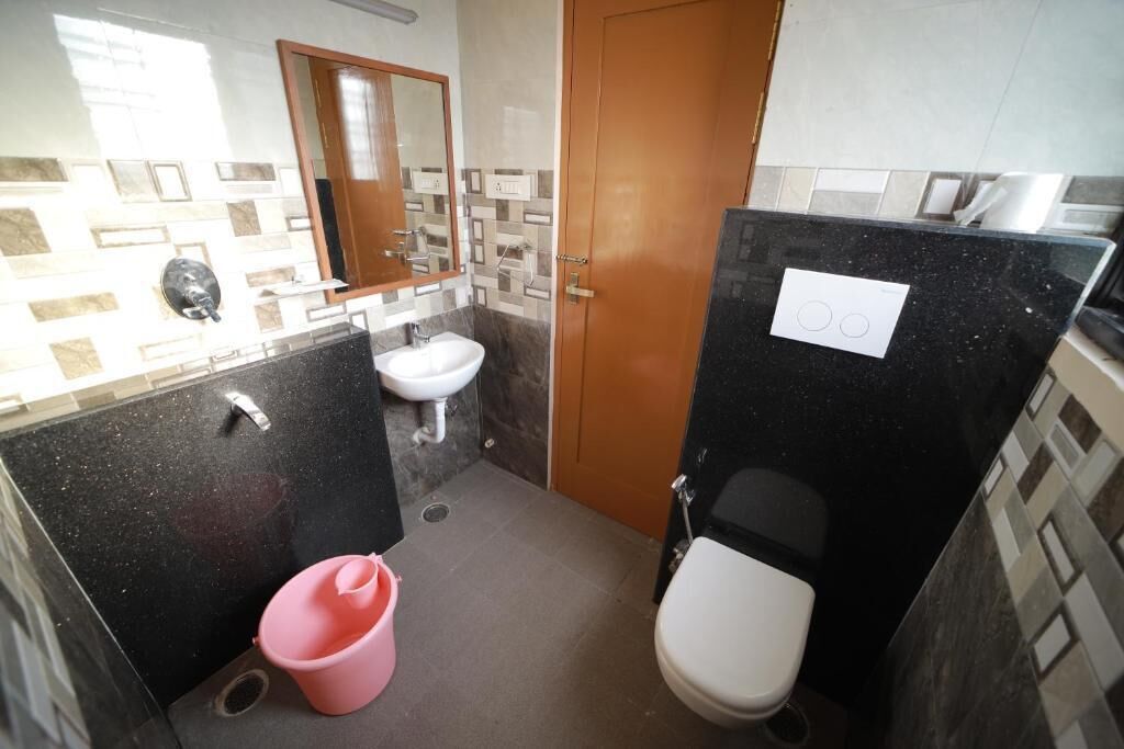 Een kleine badkamer met een wastafel, toilet en een roze emmer.
