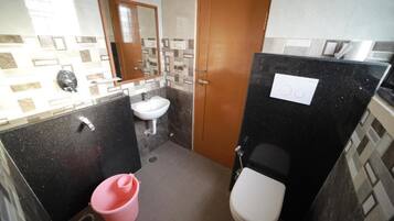 Un baño pequeño con lavamanos, inodoro y un cubo rosa.
