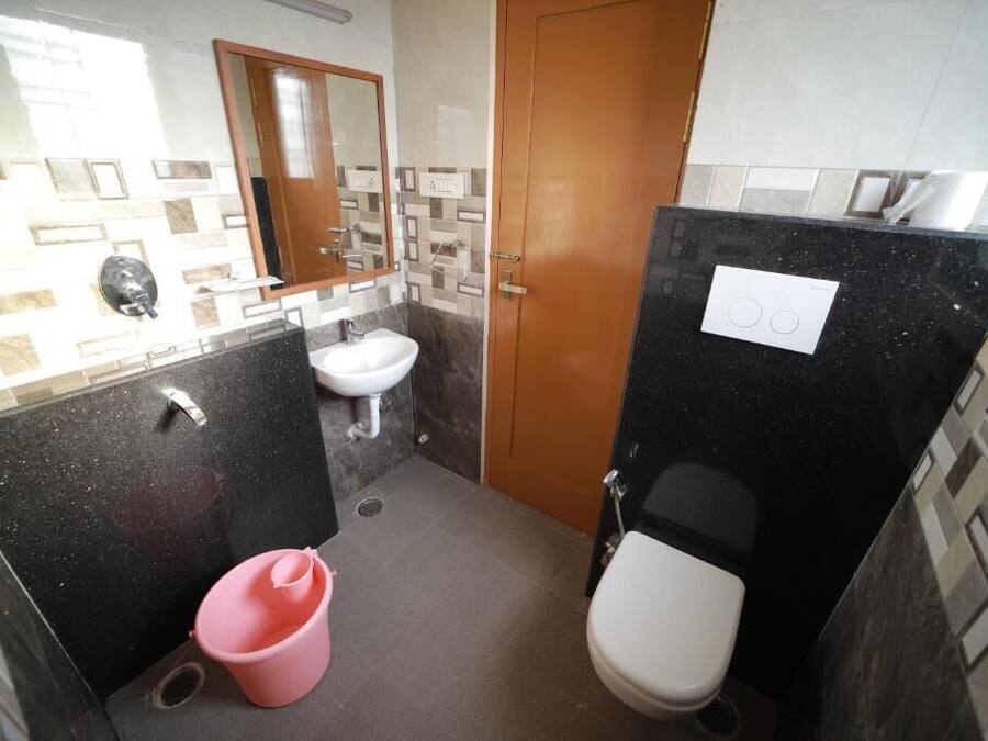 Un baño pequeño con lavamanos, inodoro y un cubo rosa.