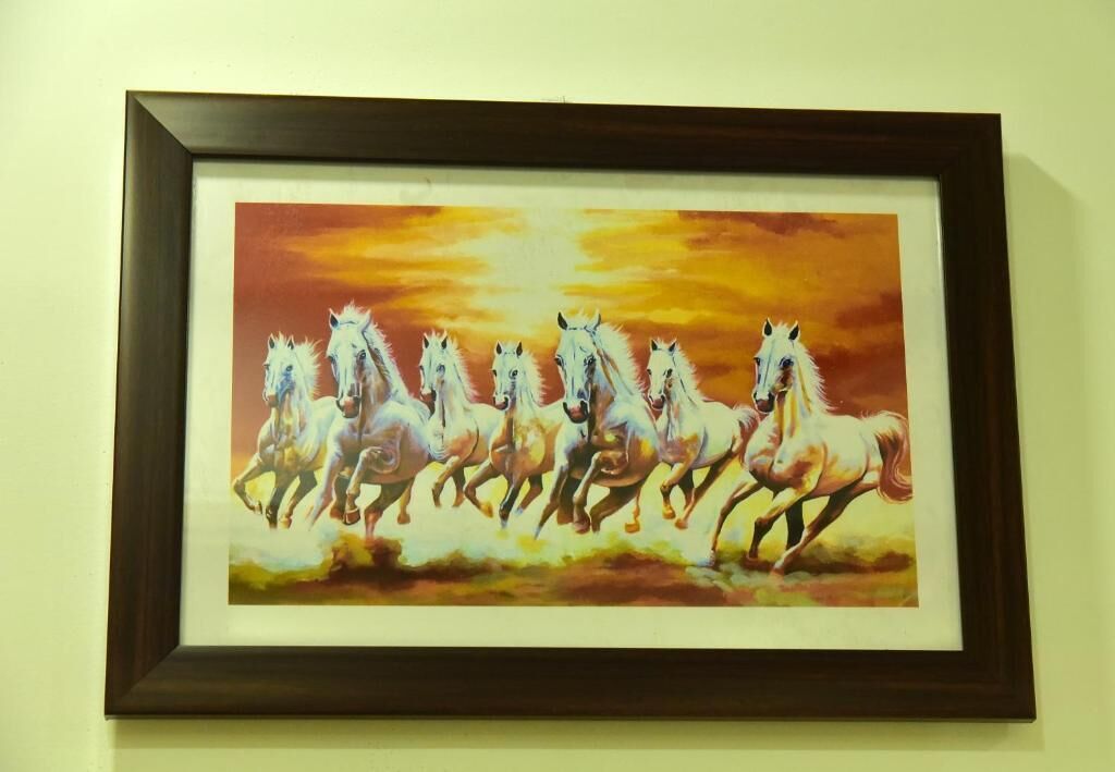 Un cuadro enmarco de caballos blancos corriendo.