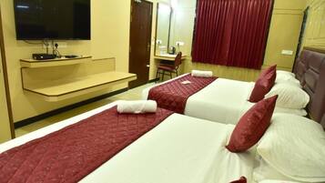 Una habitación de hotel con dos camas, televisión, escritorio y espejo.