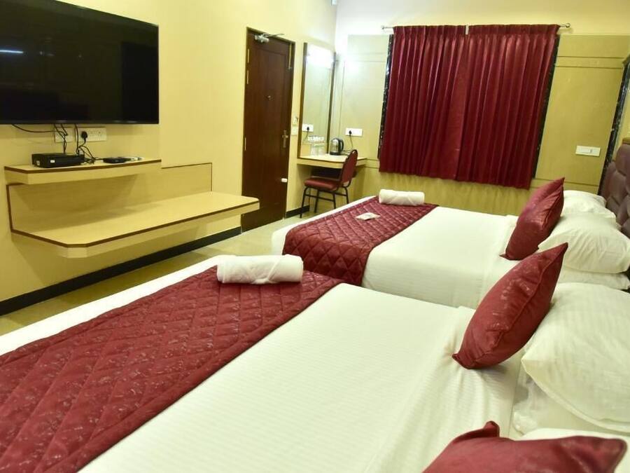 Una habitación de hotel con dos camas, televisión, escritorio y espejo.