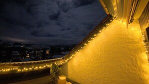 Ett snötäckt tak med ljusslingor och en måne på himlen.