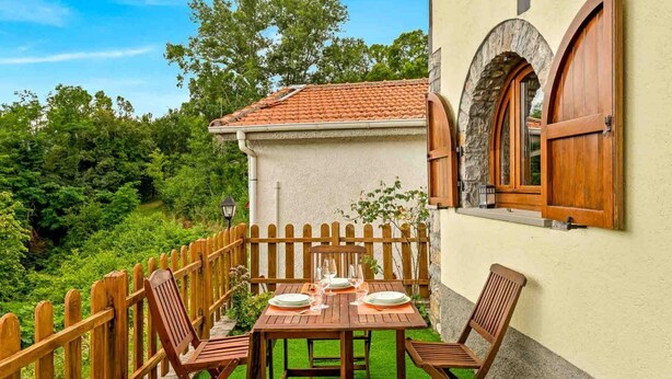 A wooden table set with plates and glasses, a wooden chair, and a stone wall with a window. - The Rustico di Zignago, located in the picturesque area of ​​Debbio, offers a unique experience that seems to transport you to another era.This rustic house is the ideal refuge for those seeking tranquility and authenticity.Ground Floor:Living Room w (Zignago)