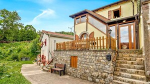 A stone-walled building with a wooden fence, a bench, and a pathway leading to a door. - The Rustico di Zignago, located in the picturesque area of ​​Debbio, offers a unique experience that seems to transport you to another era.This rustic house is the ideal refuge for those seeking tranquility and authenticity.Ground Floor:Living Room w (Zignago)