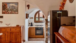 A compact kitchen with wooden cabinets, a stove, and a refrigerator. - The Rustico di Zignago, located in the picturesque area of ​​Debbio, offers a unique experience that seems to transport you to another era.This rustic house is the ideal refuge for those seeking tranquility and authenticity.Ground Floor:Living Room w (Zignago)