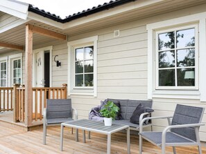 Un espace extérieur abrité, avec une table et des chaises, une plante en pot et une terrasse en bois.