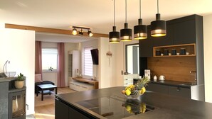 A modern kitchen with a central island, pendant lighting, and a built-in stove.