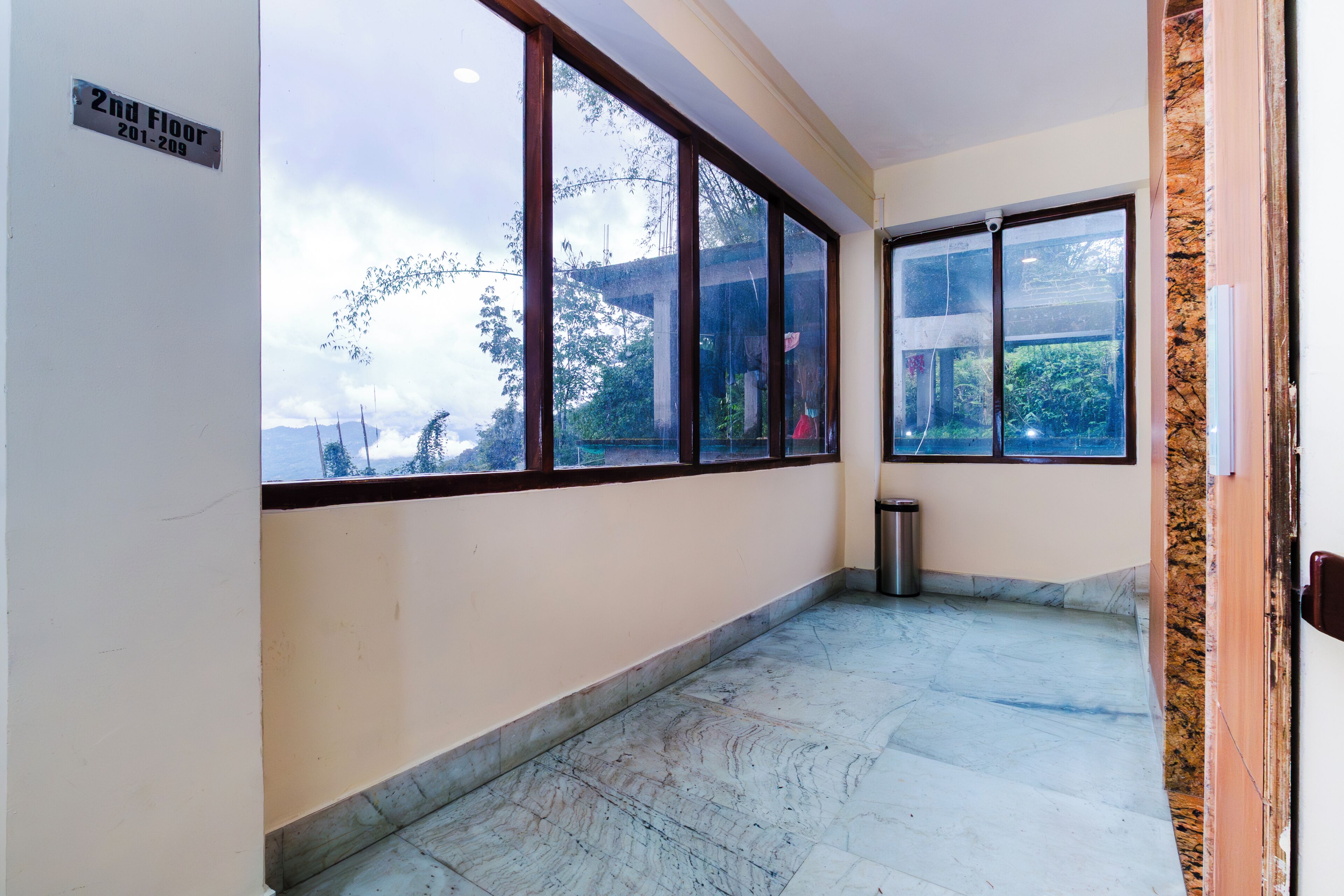 A corridor with large windows, a trash bin, and a sign indicating the 2nd floor.