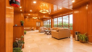 A spacious room with wooden paneling, large windows, and multiple seating areas.
