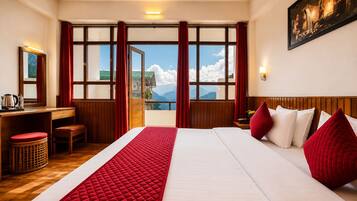 A hotel room with a large bed, a desk, a chair, and a view of mountains through large windows.