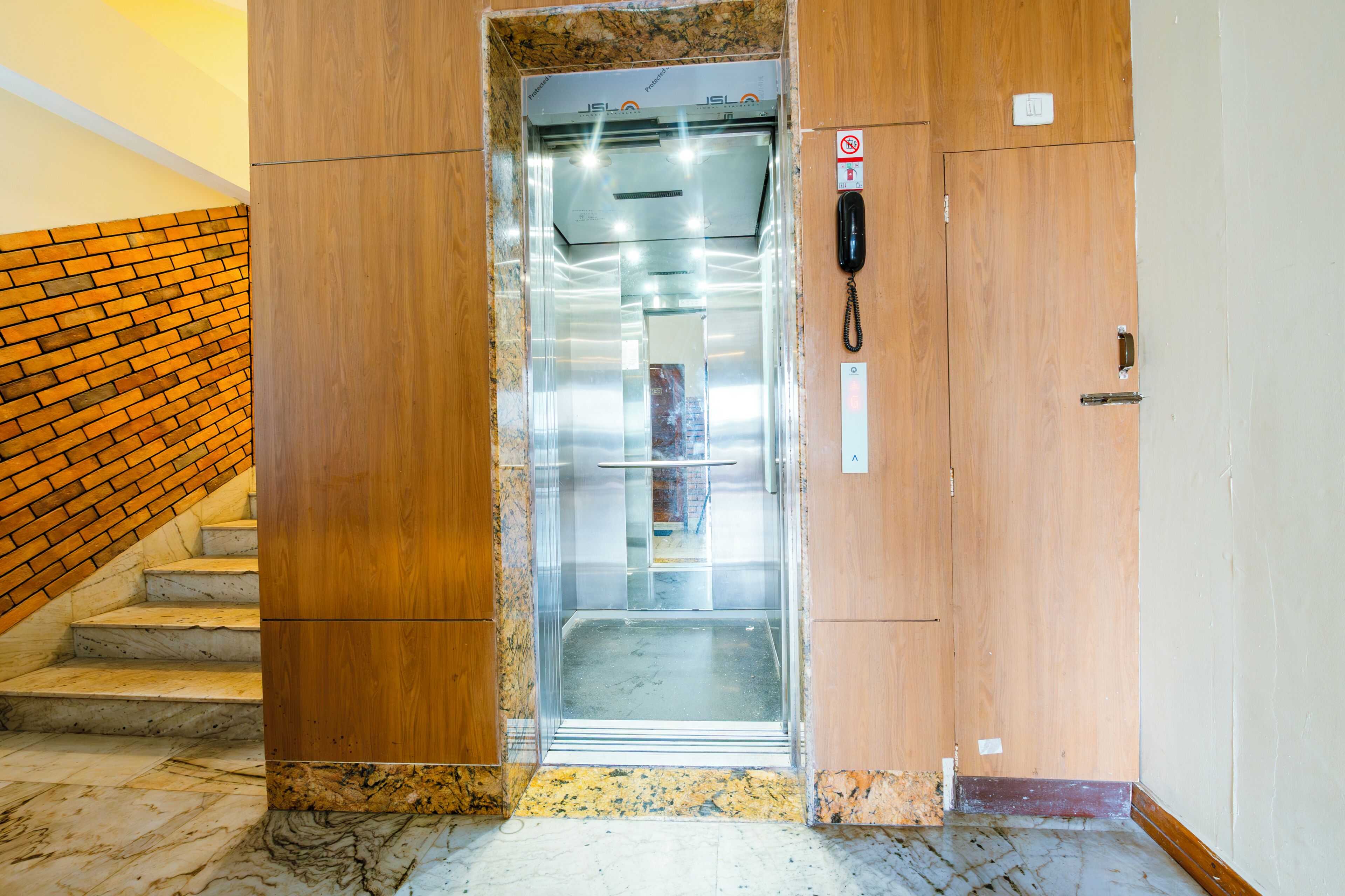 An elevator with a wooden door, a phone, and a no-smoking sign.