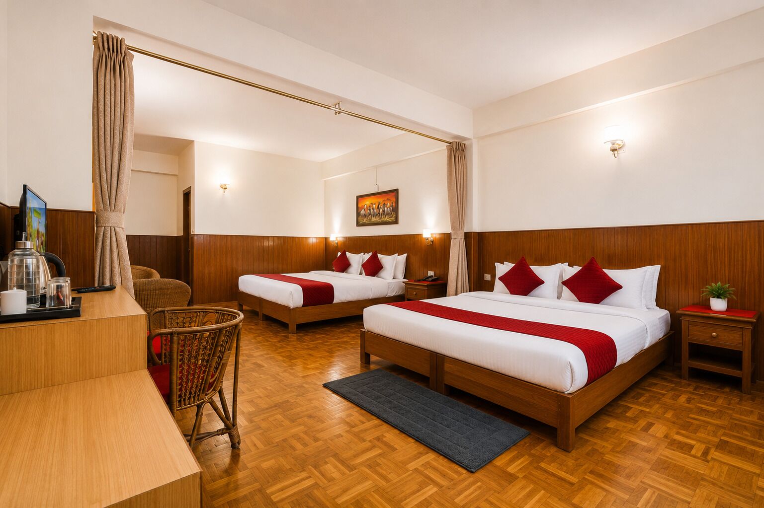 Ein Hotelzimmer mit zwei Betten, einem Schreibtisch, einem Sessel, einem kleinen Tisch, einem Nachttisch und einem an der Wand befestigten Fernseher.