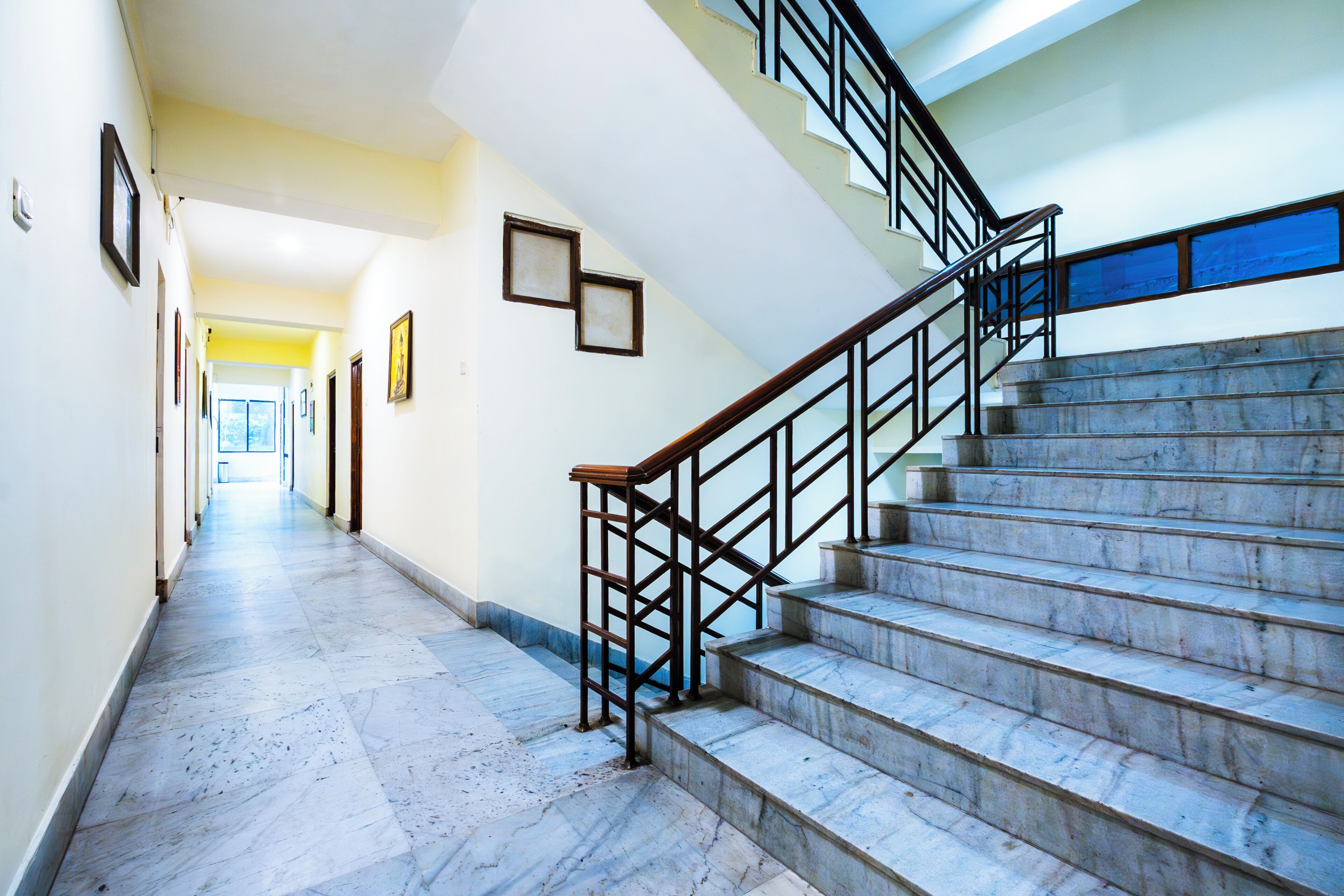 Una escalera de mármol con barandilla de metal que conduce a un piso superior.