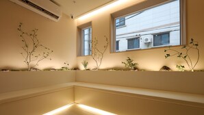 Um interior moderno com um banco, plantas e uma janela com ar condicionado.