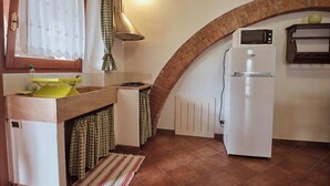 Une cuisine compacte équipée d’une cuisinière intégrée, d’un réfrigérateur blanc et d’un four à micro-ondes.