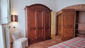Une chambre à coucher avec un lit, une armoire en bois, un radiateur et une chaise.
