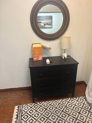 Une commode noire avec un miroir au-dessus, une lampe et une boîte posée sur la commode.