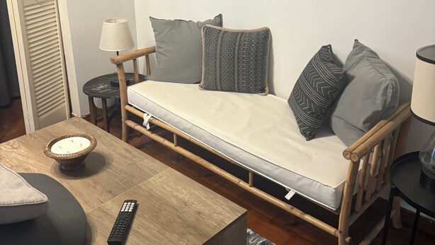 Ett kompakt vardagsrum med en soffa, ett litet bord, en lampa och abstrakt väggkonst.