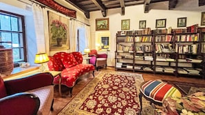 Una sala de estar acogedora con un sofá rojo, un tapete estampado y una estantería llena de libros.