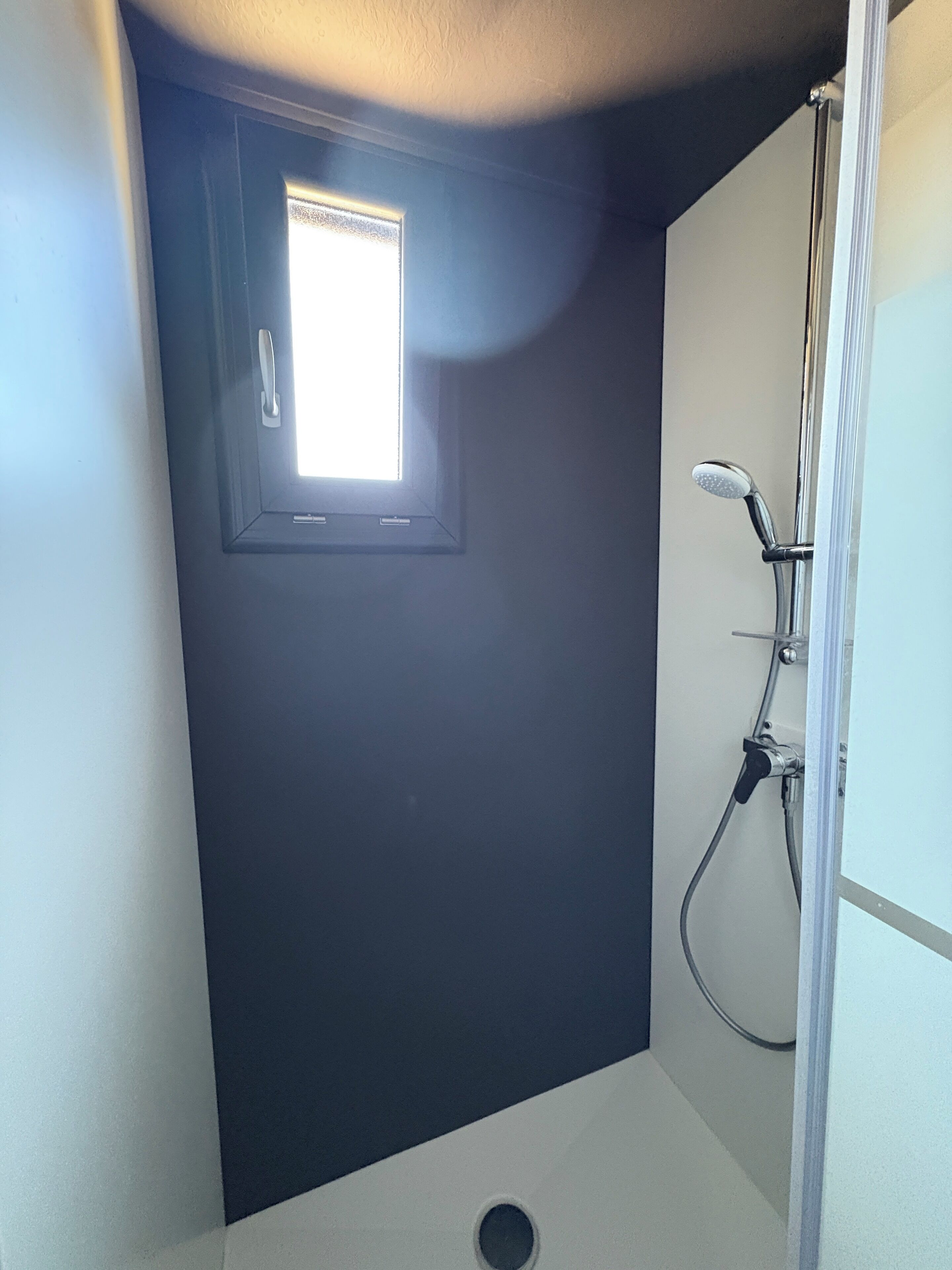 Une petite pièce sombre avec une fenêtre et une douche.