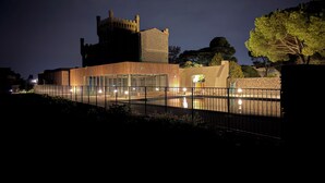 A modern building with a castle-like tower, large windows, and a paved walkway. - Chalet Prestige le Paradis - villa Cap d' Agde (Agde)