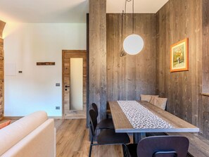 A modern dining area with a wooden table, chairs, and a pendant light. - Nice apartment for 4 guests with WIFI, TV and balcony (Carisolo)