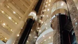 A multi-level atrium with marble columns, glass railings, and a central decorative element.