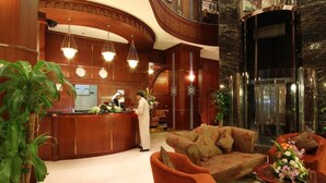 A lobby with a reception desk, a sofa, and a staircase.