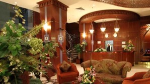 A lobby with a reception desk, a staircase, and seating areas.