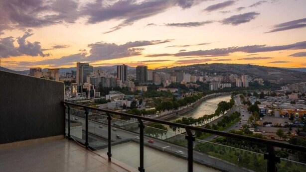 Une vue d’une ville au coucher du soleil, avec une rivière et des bâtiments en arrière-plan.