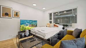 Camera d'albergo moderna con un letto, un divano, un tavolino da caffè e un'ampia finestra con vista sulla città.