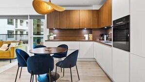 Una cucina moderna con pensili in legno, un tavolo da pranzo rotondo con sedie e una lampada a sospensione.