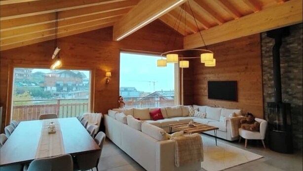 A spacious living area with a large sofa set, a dining table, and a fireplace. - Chalet Iska - Alpine elegance and warm comfort with breathtaking views (Nendaz)