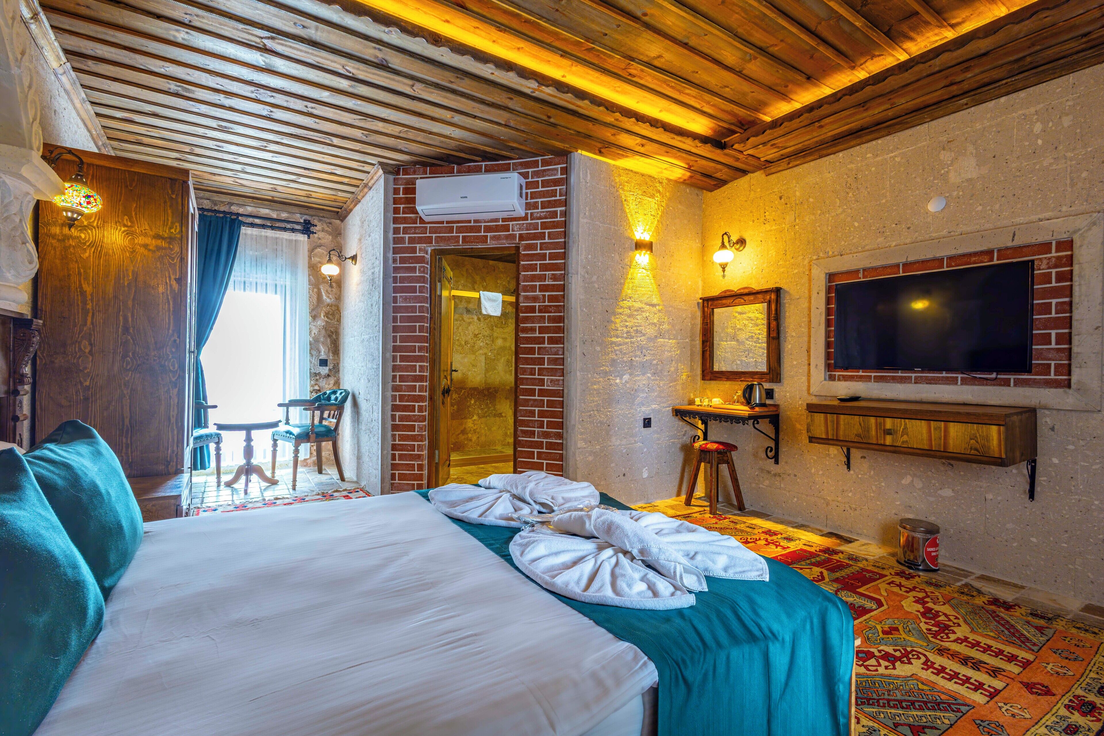 Una habitación de hotel con cama, escritorio, televisor y puerta al baño.