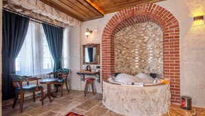 A room with a stone bathtub, wooden furniture, a mirror, and a brick wall. - Bloom Cappadocia Hotel (Nevsehir)