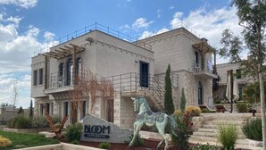 A two-story building with a stone facade, a horse statue in front, and a sign reading "BLOM CAPPADOCIA". - Bloom Cappadocia Hotel (Nevsehir)