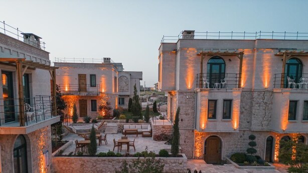 A courtyard with a swimming pool, outdoor seating, and stone buildings with warm lighting. - Bloom Cappadocia Hotel (Nevsehir)