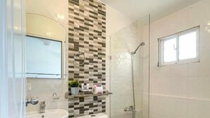 A bathroom with a tiled shower, a sink, and a toilet. - Studio Close to Agora Mall Sleeps 2 (Santo Domingo)