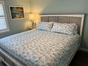 A bedroom with a bed, a nightstand, a lamp, and a painting on the wall. - Casa Blanca - Villa D08 (Siesta Key)