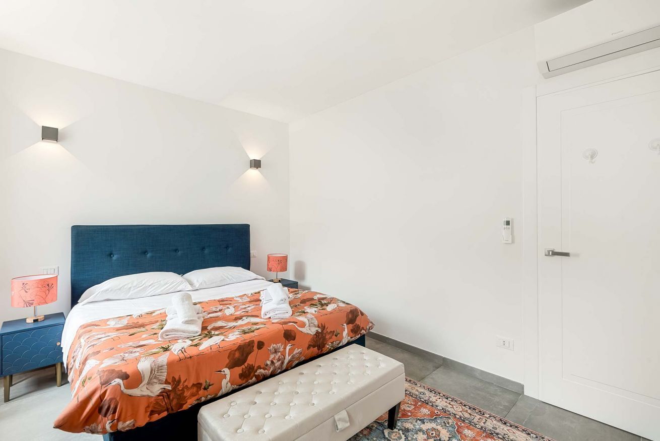 Ein Schlafzimmer mit einem Bett, einem Nachttisch, einer Sitzbank und einer Tür.