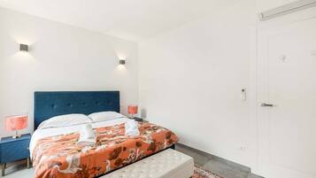 Ein Schlafzimmer mit einem Bett, einem Nachttisch, einer Sitzbank und einer Tür.